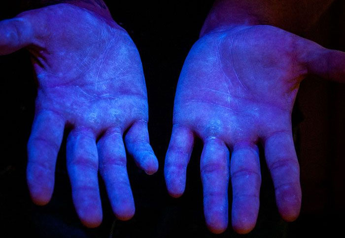 Bild 6. Fluoreszierendes Material unter UV-Licht, um den Deckungsgrad an den H&auml;nden des Menschen zu zeigen (Quelle www.glogerm.com)
